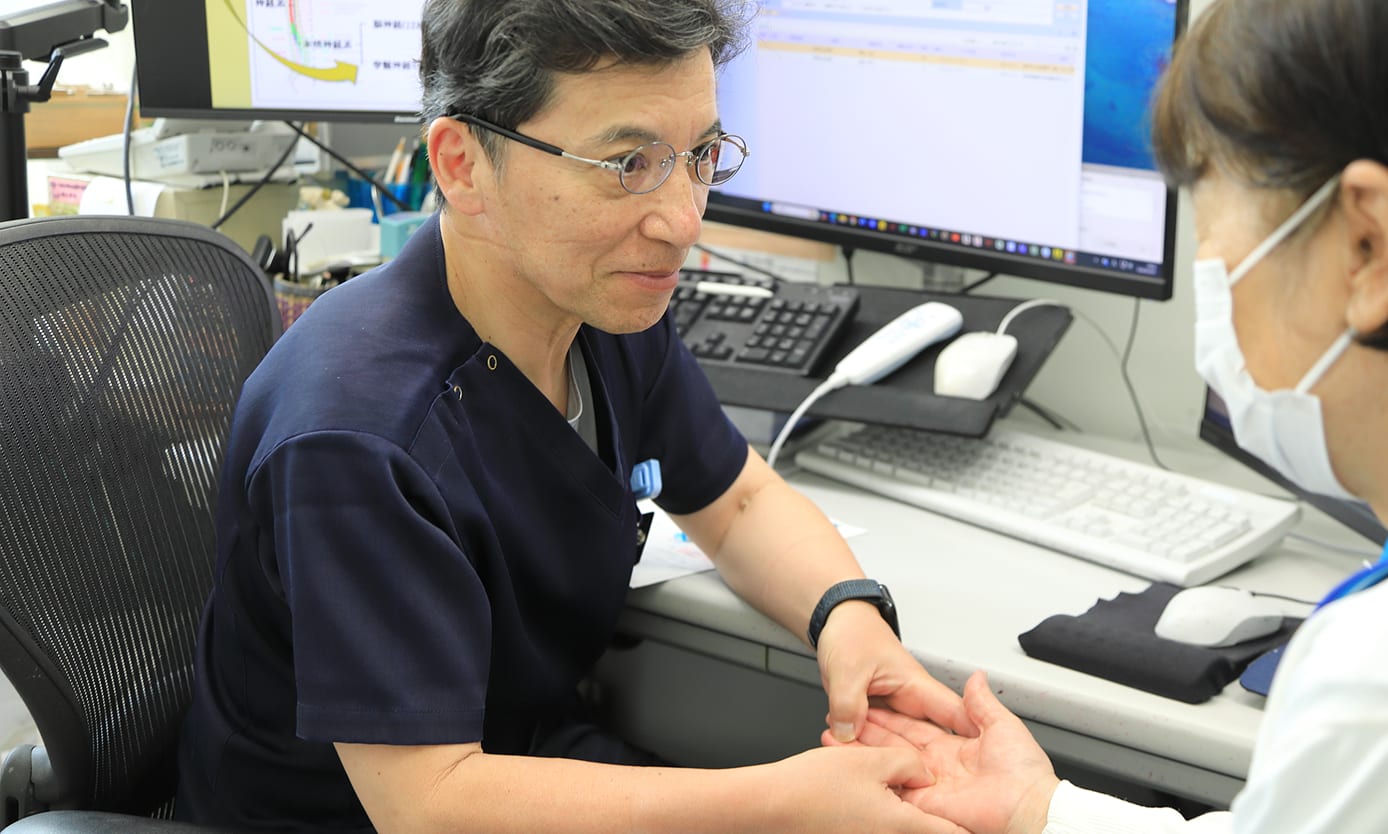 診察室で医師が患者の手を診察している様子
